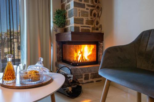 a fireplace in a living room with a table and a chair at Spiliara-Apartments in Axós