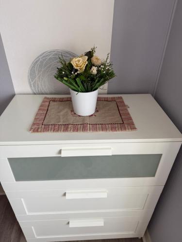 un tiroir blanc avec un vase de fleurs sur lui dans l'établissement Du côté de chez, à Houlgate