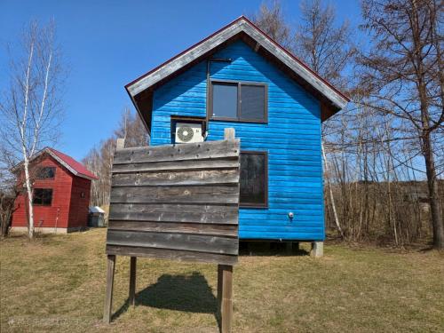 a blue house sitting on top of a field at Auberge Ninguruforet in Biei