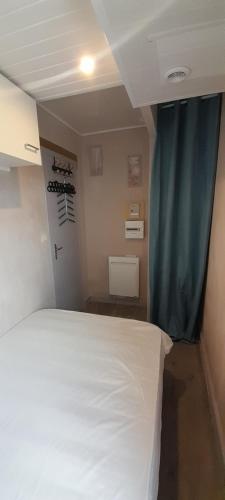 une chambre avec un lit blanc et un rideau bleu dans l'établissement T2 Saint Palais sur mer, 500 m plage Nauzan, Résidence Cap Atlantic, à Saint-Palais-sur-Mer