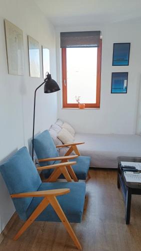 a living room with a blue chair and a bed at Kiscsillag Vendégház in Budapest