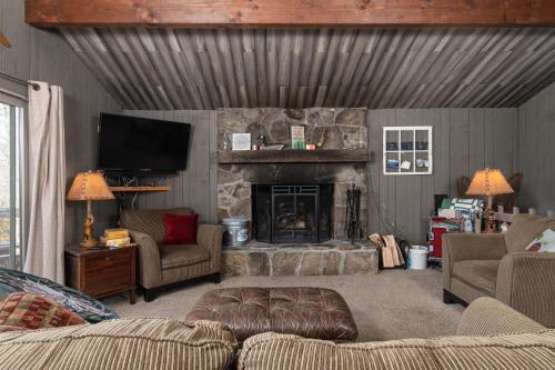 a living room with a stone fireplace and a tv at Bear Hill Cabin cabin in Ludlow
