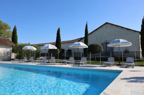 una piscina con sillas y sombrillas en La Cannonerie, en Réaux