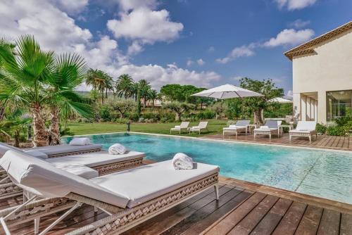 - une piscine avec 2 chaises longues et un parasol dans l'établissement villa Olivia, à Saint-Tropez