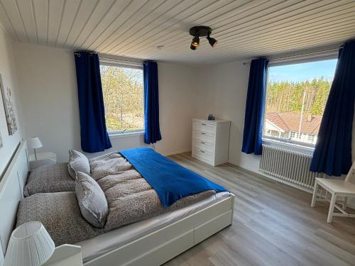 a bedroom with a bed and blue curtains and a window at Familjehus Villa Kunterbunt in Alstermo