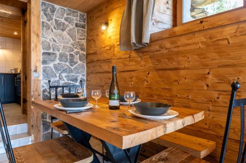- une table en bois avec 2 verres et une bouteille de vin dans l'établissement La Bergerie, à La Giettaz