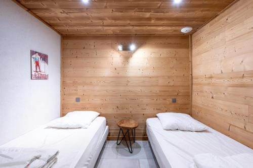 deux lits dans une chambre aux murs en bois dans l'établissement La Bergerie, à La Giettaz