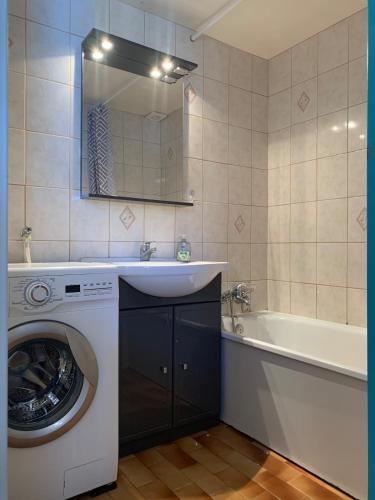 La salle de bains est pourvue d'un lave-linge, d'un lavabo et d'une baignoire. dans l'établissement Charmante maison avec sa terrasse au soleil, au Cap d'Agde