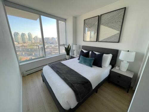 a bedroom with a large bed with a large window at Condo Downtown Vancouver - Near Rogers Arena & BC Place w Parking in Vancouver