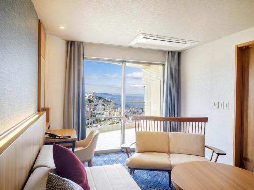 a hotel room with a couch and a large window at KAMENOI HOTEL Atami in Atami