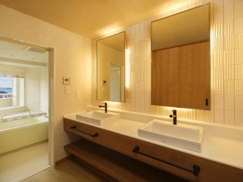 a bathroom with two sinks and a large mirror at KAMENOI HOTEL Atami in Atami