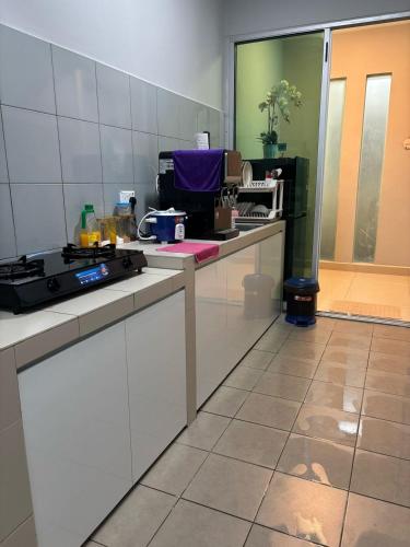 a kitchen with a stove and a counter top at Anggerik Homestay - Palm Garden Apartment in Lahad Datu