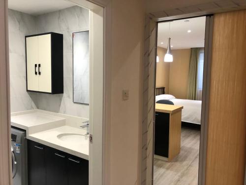 a bathroom with a sink and a room with a bed at Praise Hotel Xujiahui Zikawei Shanghai Stadium 上海徐家汇赞寓酒店上海体育馆地铁站店 in Shanghai