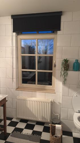a bathroom with a window and a checkered floor at Countryhouse Zuid-Limburg in Nuth