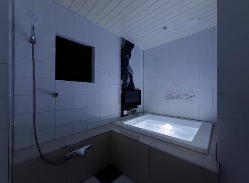 a bathroom with a bath tub and a tv at HOTEL 翠 sui -TIMELESS GARDEN- in Koshido