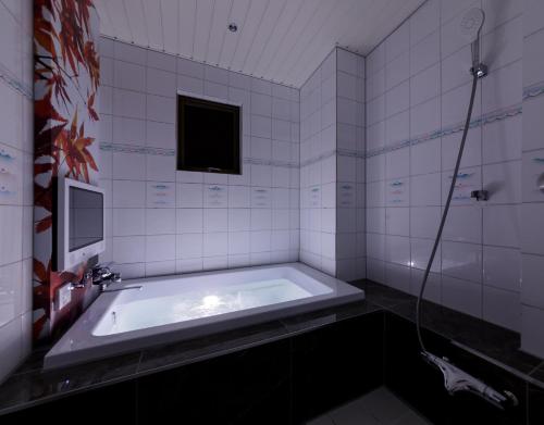 a bathroom with a tub with a television and a tv at HOTEL 翠 sui -TIMELESS GARDEN- in Koshido