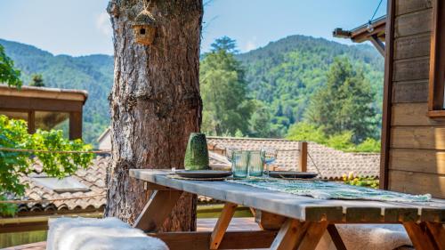 a wooden table with plates and glasses on top of a tree at Le Chalet - Les Lodges de Praly in Les Ollières-sur-Eyrieux