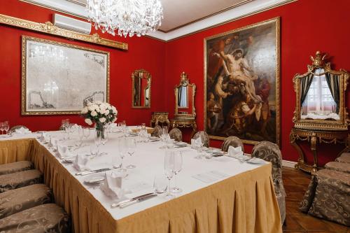 a long table in a red room with a painting at Alchymist Grand Hotel and Spa - Preferred Hotels & Resorts in Prague