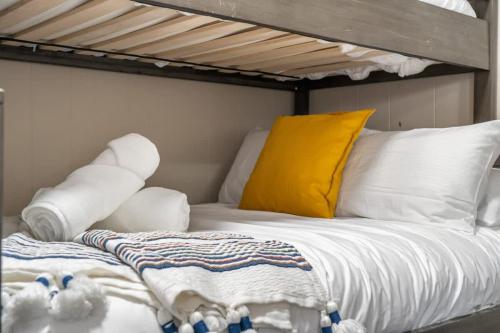 a bed with white pillows and a yellow pillow at Raptor Retreat Family in Drumheller