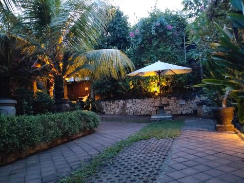 a patio with a table and an umbrella at Mandox Bali Homestay in Nusa Dua