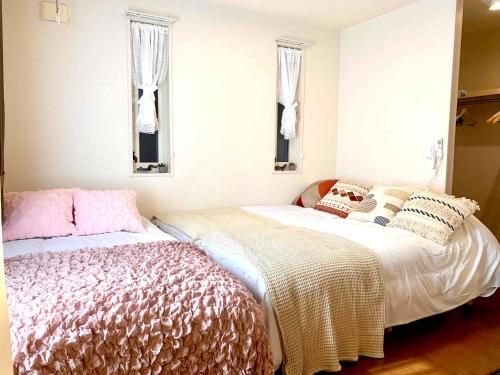 a bedroom with two beds and two windows at Monzennakacho Royal Residence in Tokyo