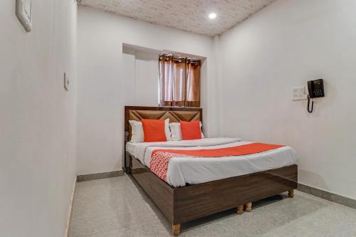 a small bedroom with a bed with orange pillows at Hotel O Sun View in Ludhiana