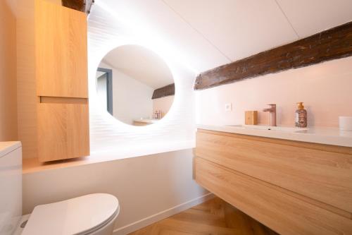 La salle de bains est pourvue de toilettes blanches et d'un miroir circulaire. dans l'établissement 2 Chambres, proche des plages, parking, à Fréjus