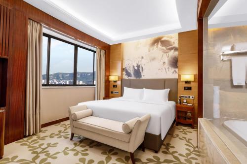 a bedroom with a bed and a tub and a window at Enlux Hotel in Jinan