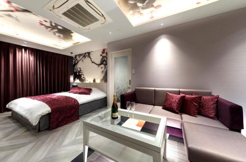 a bedroom with a bed and a couch and a table at HOTEL 翠 sui -TIMELESS GARDEN- in Koshido