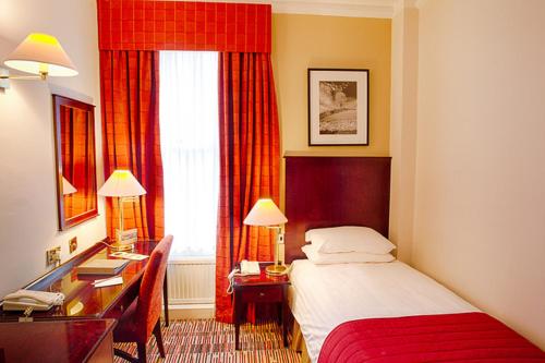a hotel room with a bed and a desk and a window at Old Swan Hotel in Harrogate