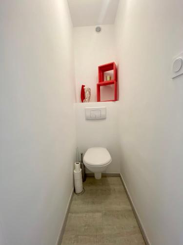 La salle de bains est pourvue de toilettes et d'une étagère rouge. dans l'établissement LE BOUCANET - APPARTEMENT CLIMATISÉ ENTIEREMENT RÉNOVÉ POUR 4 PERSONNES AVEC PARKING PRIVATIF, au Grau-du-Roi