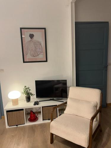 a living room with a chair and a desk with a computer at Les Capucines, comme chez soi, loin de chez soi in Aubenas