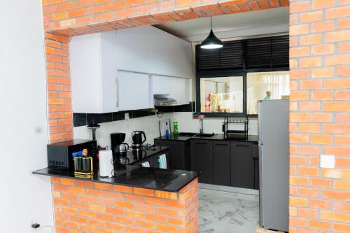 una cucina con mobili bianchi e un muro di mattoni di Make Good Apartment a Kigali