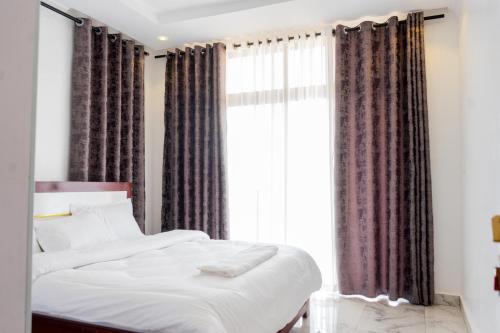 una camera da letto con un letto e una grande finestra di Make Good Apartment a Kigali