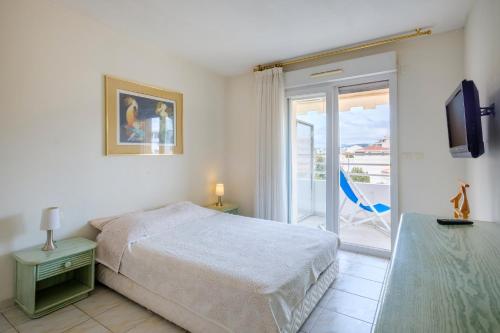 une chambre blanche avec un lit et un balcon dans l'établissement Appartement Jardin de Monfleury, à Cannes