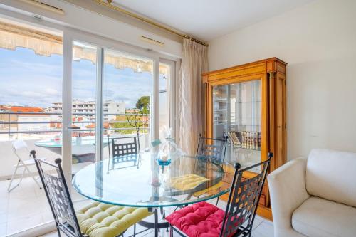 une salle à manger avec une table en verre et un balcon dans l'établissement Appartement Jardin de Monfleury, à Cannes
