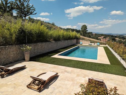 une piscine avec deux chaises longues et une piscine dans l'établissement Villa Olivera, à Saint-Sernin