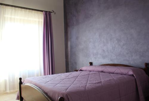 a bedroom with a purple bed and a window at Agriturismo La Casa di Bacco in Agrigento