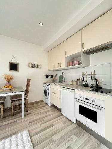 une cuisine avec des armoires blanches, une table et un évier dans l'établissement Cozy appartement Bords de Marne, à Saint-Maur-des-Fossés