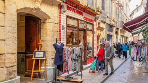 a group of people walking in front of a clothing store at Au coeur de la vieille ville, Chambre privée indépendante in Sommières