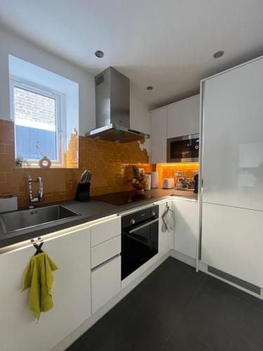 a kitchen with white cabinets and a sink at Cozy and Peaceful Apartment with Terrace in Hackney in London