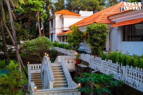 a house with a white fence and stairs in front of it at 5bhk Luxurious Heritage Villa La Bougainvillea with Pvt Pool, Bathtub, BBQ at Porvorim in Porvorim