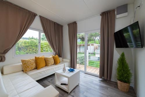 a living room with a white couch and a large window at Camping Village Baia Azzurra in Castiglione della Pescaia