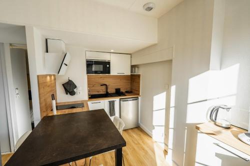 une cuisine avec des placards blancs et une table noire dans l'établissement Nice T2 in Bordeaux near the Stadium, à Bordeaux