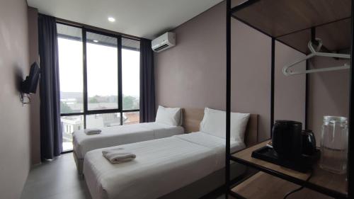 una camera d'albergo con due letti e una tv di VNC Alam Sutera Hotel Powered by Archipelago a Dongkal