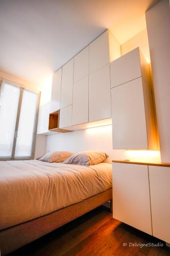 - une chambre avec un lit et des armoires blanches dans l'établissement Appartement Design - Lumineux & Confort - 5mn de Paris, à Bagnolet
