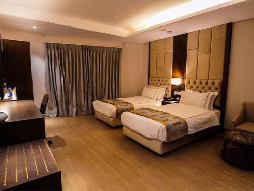 a hotel room with two beds and a couch at Oasis Hotel in Comilla