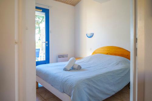 une chambre avec un lit blanc avec une tête de lit en bois dans l'établissement Maison mitoyenne de vacances - piscine commune et espaces verts - 4 personnes, à Saint-Hilaire-de-Talmont