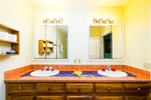 a bathroom with two sinks and two mirrors at Bananarama Dive & Beach Resort in West Bay
