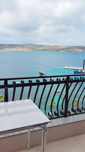 a table on a balcony with a view of the water at Sapore di Mare apartment in St. Paul's Bay
